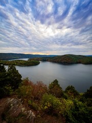 Fototapeta na wymiar Gorgeous view of Raystown Lake from Hawn’s Overlook near Altoona, Pennsylvania in the fall right before sunset with a view of the dramatic blue sky filled with clouds and pops of pink with foliage.