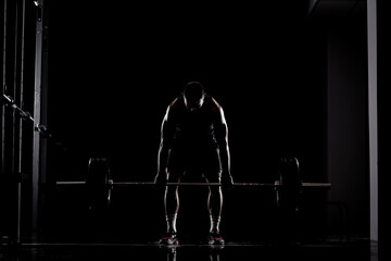 Athlete lifting barbell. Silhouette of a muscular man