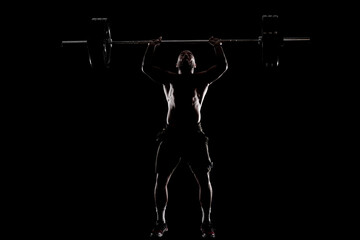 Fototapeta na wymiar Athlete lifting barbell. Silhouette of a muscular man