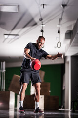 Fototapeta na wymiar Muscular athlete power lifting a kettlebell. Man working out indoors