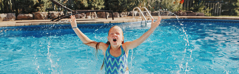 Cute adorable girl swimming splashing in pool on home backyard. Kid child enjoying having fun in...