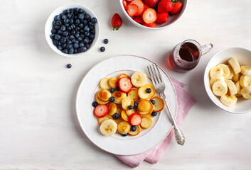 Breakfast with tiny pancakes and berries, top view
