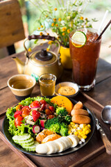 Homemade fruit vegetable salad, honey mustard, tomato,strawberry,orange,apple,banana,maize and sausage in bowl  with lemon tea on wooden background.Selective focus...