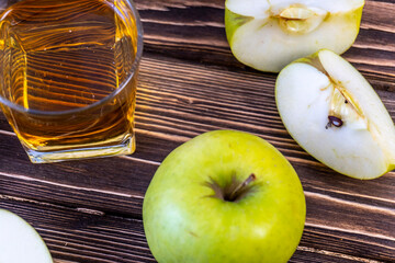 Green apples and glass with apple juice on wooden background