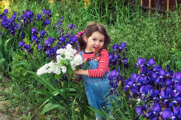 A happy little girl holds a blooming white lilac in her hands