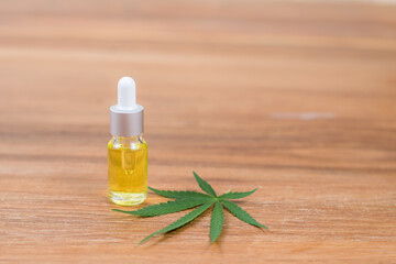 Cannabis oil extracts in dropper bottle and cannabis leaf on wooden background