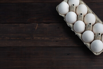 Fresh chicken eggs in a package, raw eggs in a white shell in a box. Top view copy space, wooden background.
