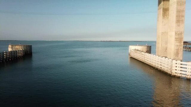 Aerial drone view of shipping channel of the Gulf Intercoastal Waterway into Corpus Christi Bay; flying under JKF Causeway bridge along the shore line; North Padre Island, Corpus Christi Texas