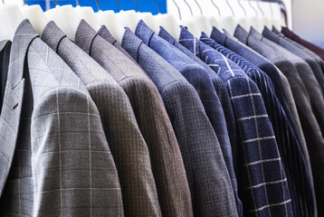 Fototapeta premium men's jackets in check and stripes hang on hangers in the atelier
