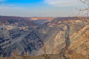 Fototapeta premium Huge iron ore quarry with working dump trucks and excavators