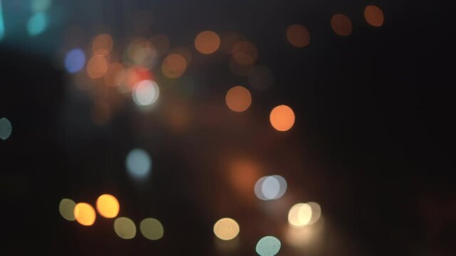 Beautiful sparkling bokeh in a dark blurred background at night. Round colorful bokeh shines from car headlights on a city street.
