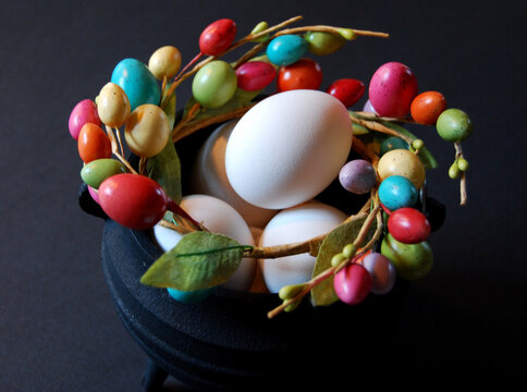 Cast iron cauldron with white eggs and wreath of small pastel eggs