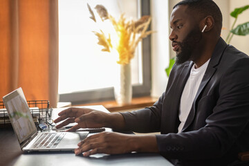 African American man is participating in an online conference sitting at the table at home. Remote...