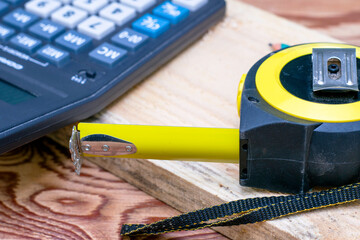 construction meter-tape measure calculator for calculations pencil and wooden board are on the workbench