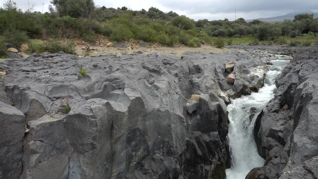 volcanic rock of Sicily nature split by a fault and smoothed by the waters flowing in a gorge of Simeto river 