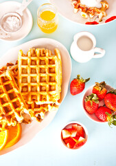 Freshly homemade baked waffles with strawberries and honey.
