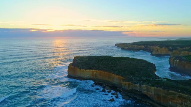 Aerial view of rocks and a rippling sea of ​​London Bridge, Australia at sunset