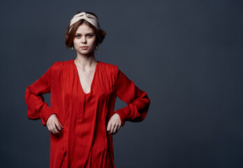 Attractive woman in red dress decorating turban on her head studio cropped view