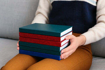 Woman with stack of books sitting on sofa