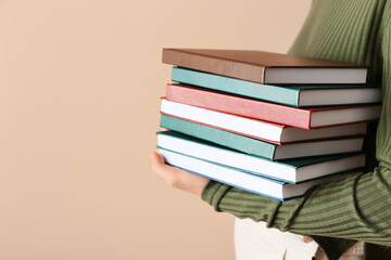 Woman with stack of books against color background