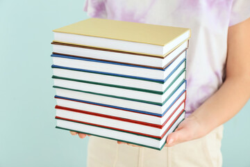 Woman with stack of books against color background