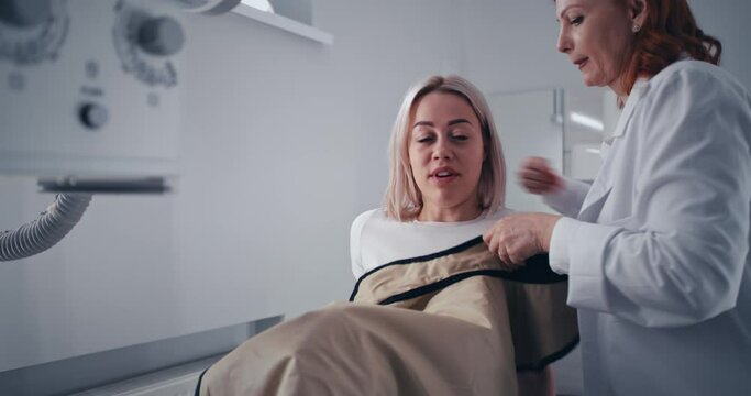 Female patient speaking with doctor during X ray scanning preparation