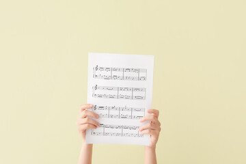 Woman holding music notes on color background