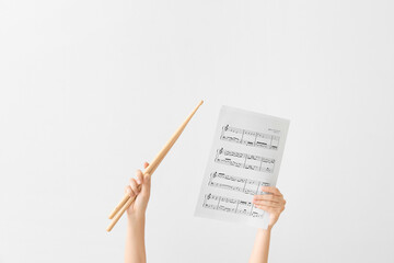 Woman holding drumsticks and music notes on light background