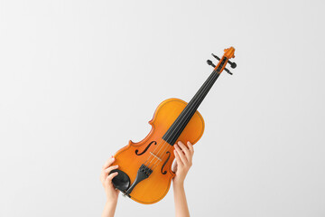 Woman holding violin on light background