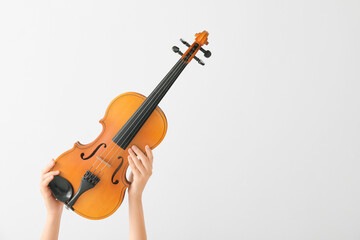 Woman holding violin on light background