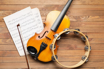 Violin, tambourine and music notes on wooden background