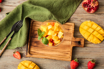 Glass bowl with salad and tropical fruits on table