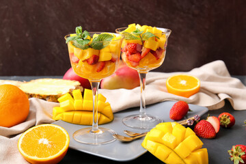 Glass bowls with tropical fruit salad on dark background
