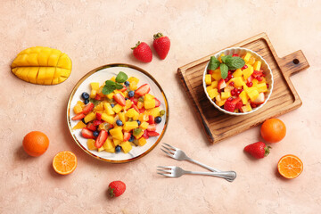 Bowl and plate with tropical fruit salad on color background