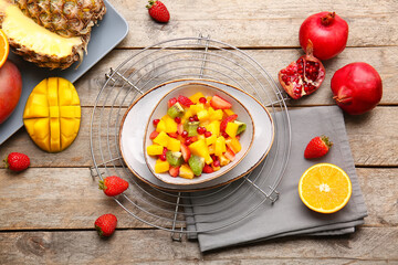 Bowl with tropical fruit salad on wooden background