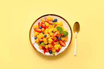 Plate with tropical fruit salad on color background