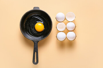 Frying pan with raw egg on color background