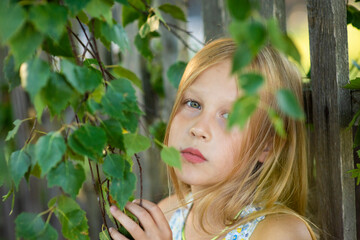 blonde girl portrait in green foliage, selective focus