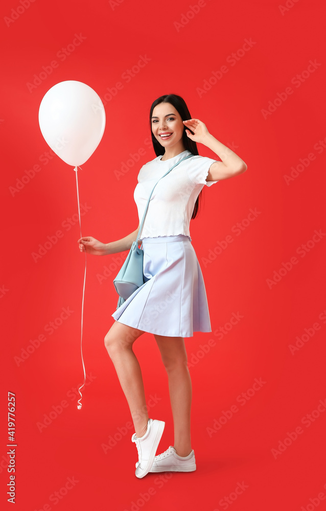 Poster Beautiful young woman with balloon on color background