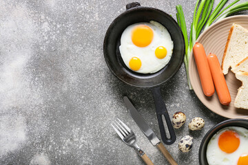 Frying pans with tasty eggs on grunge background