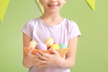 Cute little girl with Easter eggs on color background