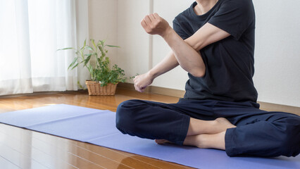 Obraz premium A man stretching at home.Shoulder stretch