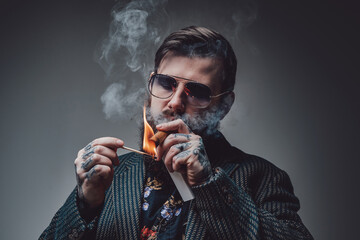 Portrait of a handsome bearded guy dressed in custom luxurious clothing. Man smoking cuban cigar in...