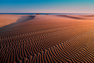 Desert background of a Close-up view of orange nature texture of the sand and dunes rippled surface. Play of lights and darks