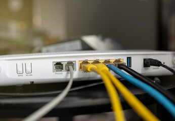 Internet router connected with blue yellow and white LAN cable place on wooden  table. Selective focus.