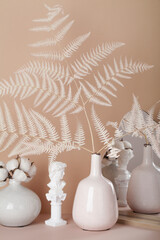 cozy and soft home decor concept. vases with dried grass, candles, small statue, mirror and wooden frame on beige background. Interior.