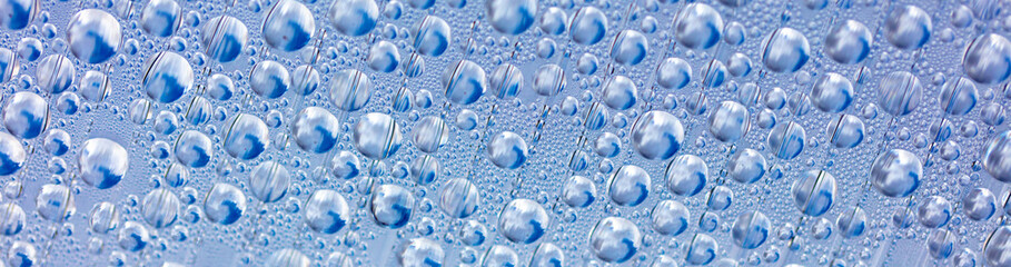 Water drops on blue glass as an abstract background.