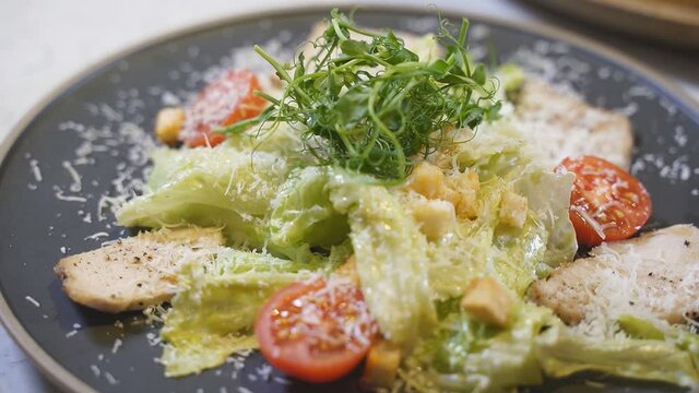 Close-up of caesar salad with chicken fillet and parmesan cheese. slow-motion