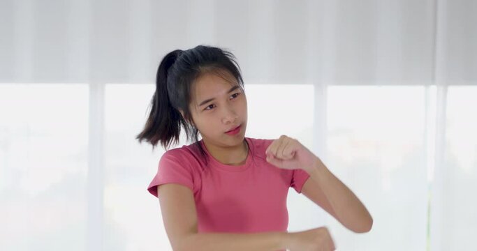 Asian woman air punch boxing for muscle workout weight training exercise at home in pink sportswear. Take care health in quarantine coronavirus with new normal social distancing