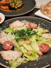 Delicious caesar salad close-up on a black plate.